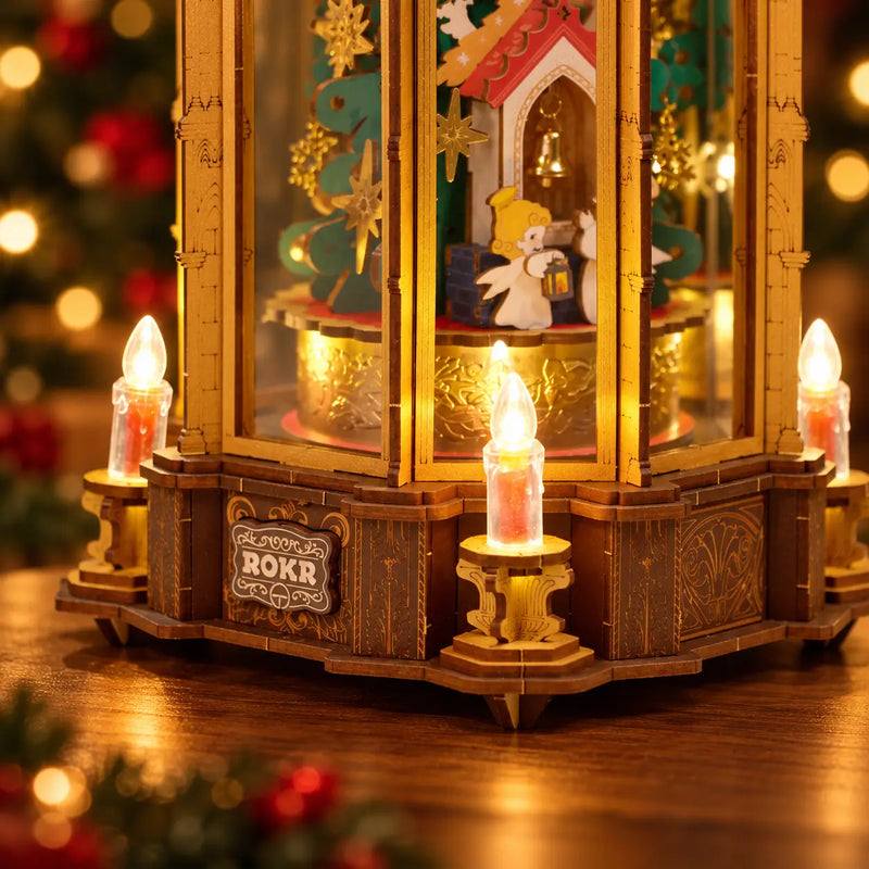 Glowing electronic candle lights around the engraved wooden base and miniature angel scene of the ROKR AMB01 pyramid.