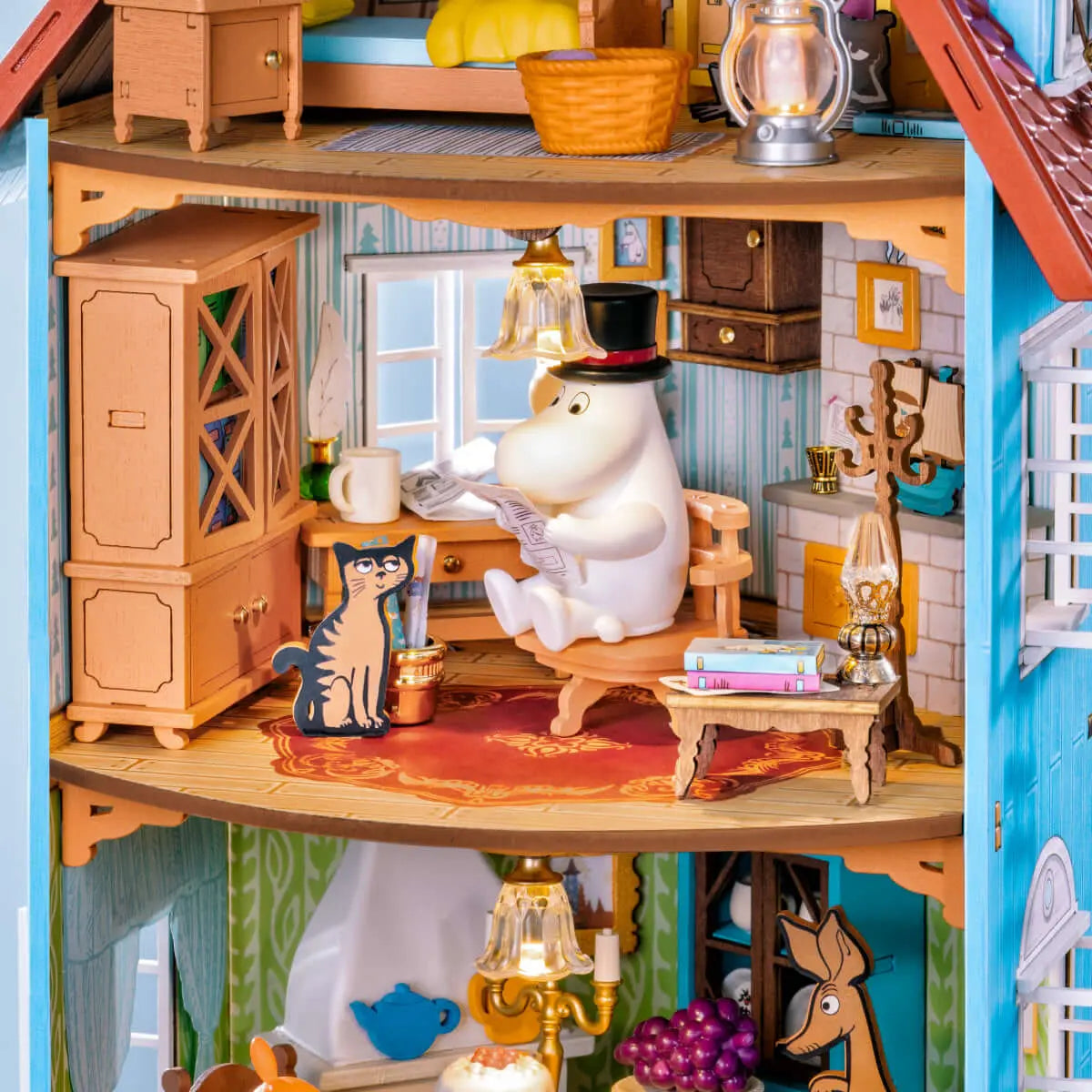 Close-up of Moominpappa reading beside a cat in the furnished Moominhouse study
