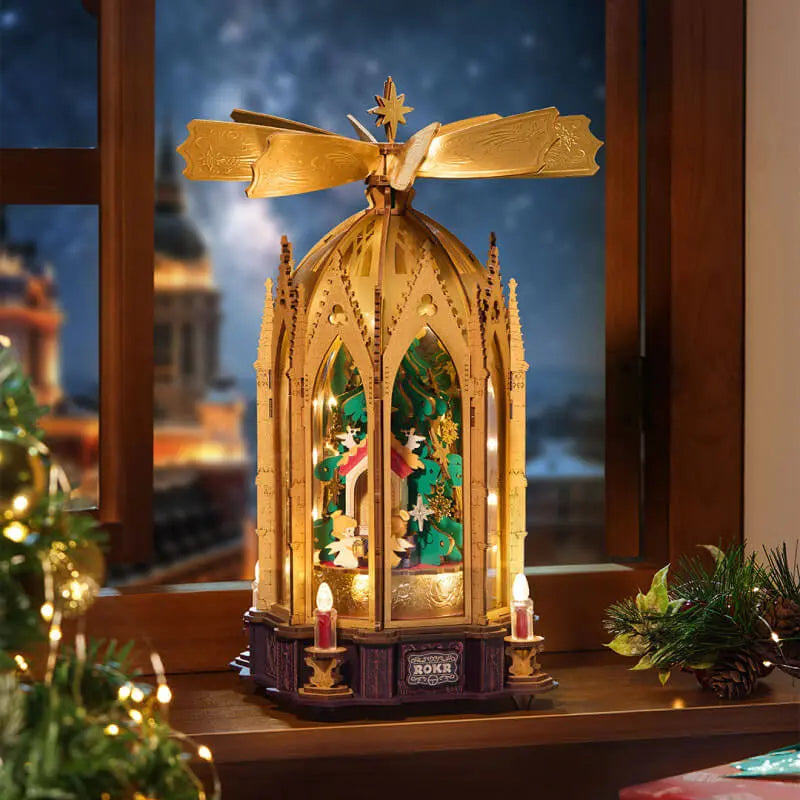 Illuminated ROKR AMB01 Christmas pyramid on a windowsill beside festive greenery and a small Christmas tree