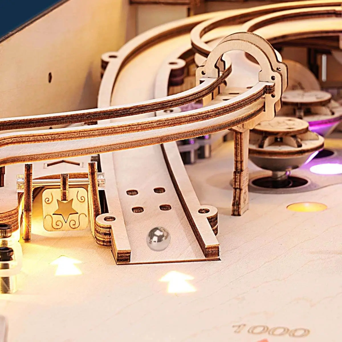 Close-up of the wooden pinball machine elevated ramp and curved track carrying a steel ball across the playfield