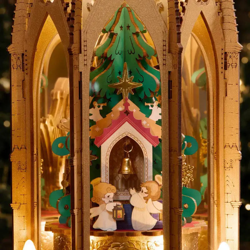 Miniature angels and a bell beneath the decorated Christmas tree inside the illuminated ROKR AMB01 pyramid.