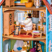 Close-up of Moominpappa reading beside a cat in the furnished Moominhouse study