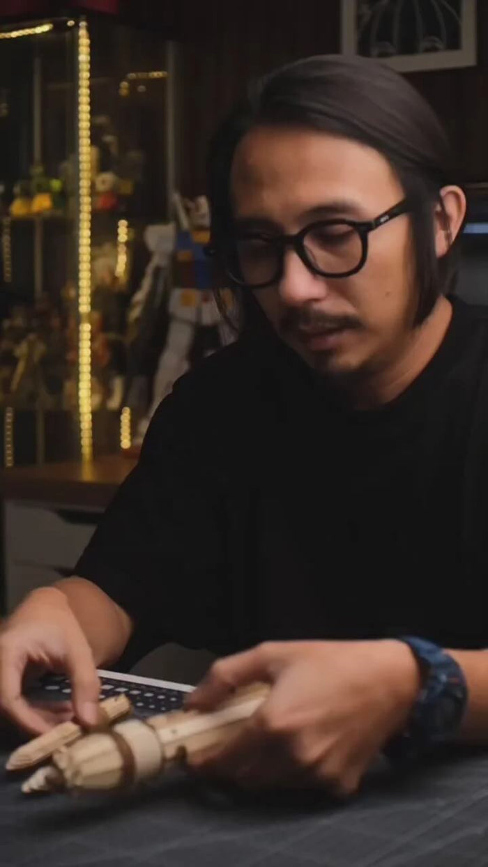 Builder assembling a detailed wooden mechanical model kit by hand