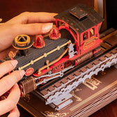 Hands assembling the black and red Century Train steam locomotive on its wooden track