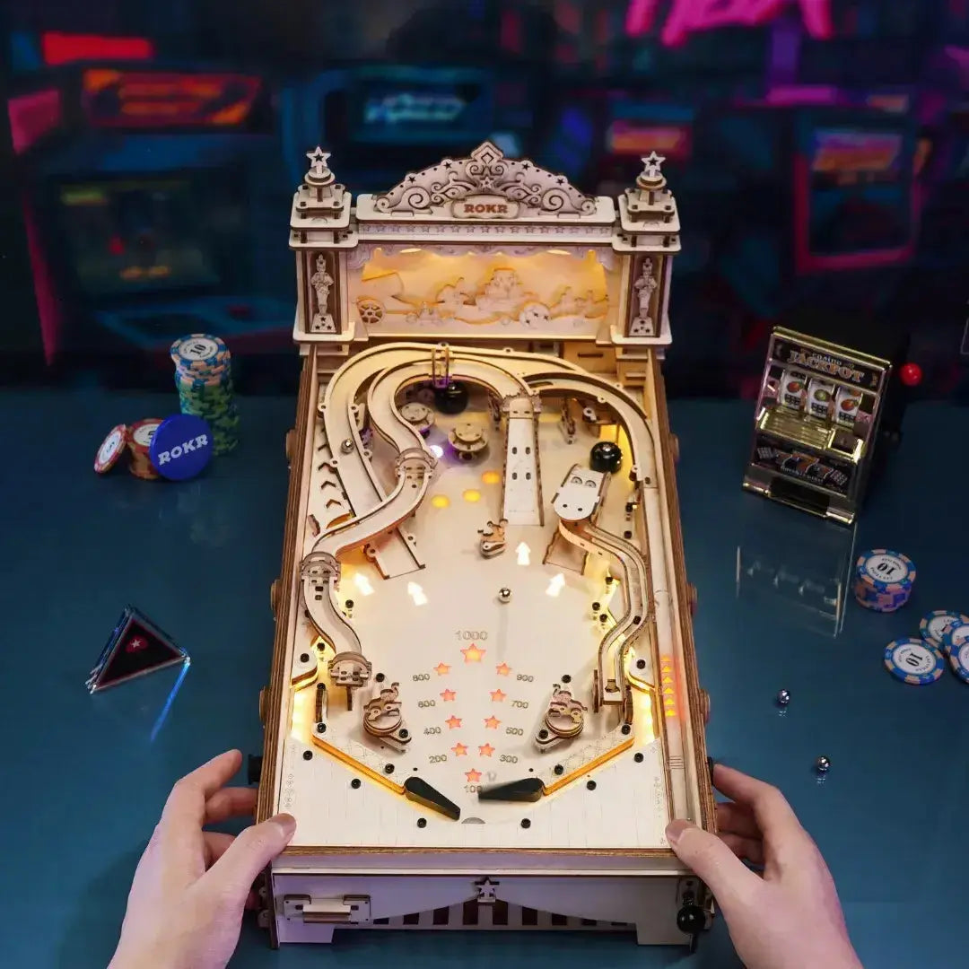 Hands playing the wooden pinball machine tabletop game with illuminated tracks, flippers and scoring targets